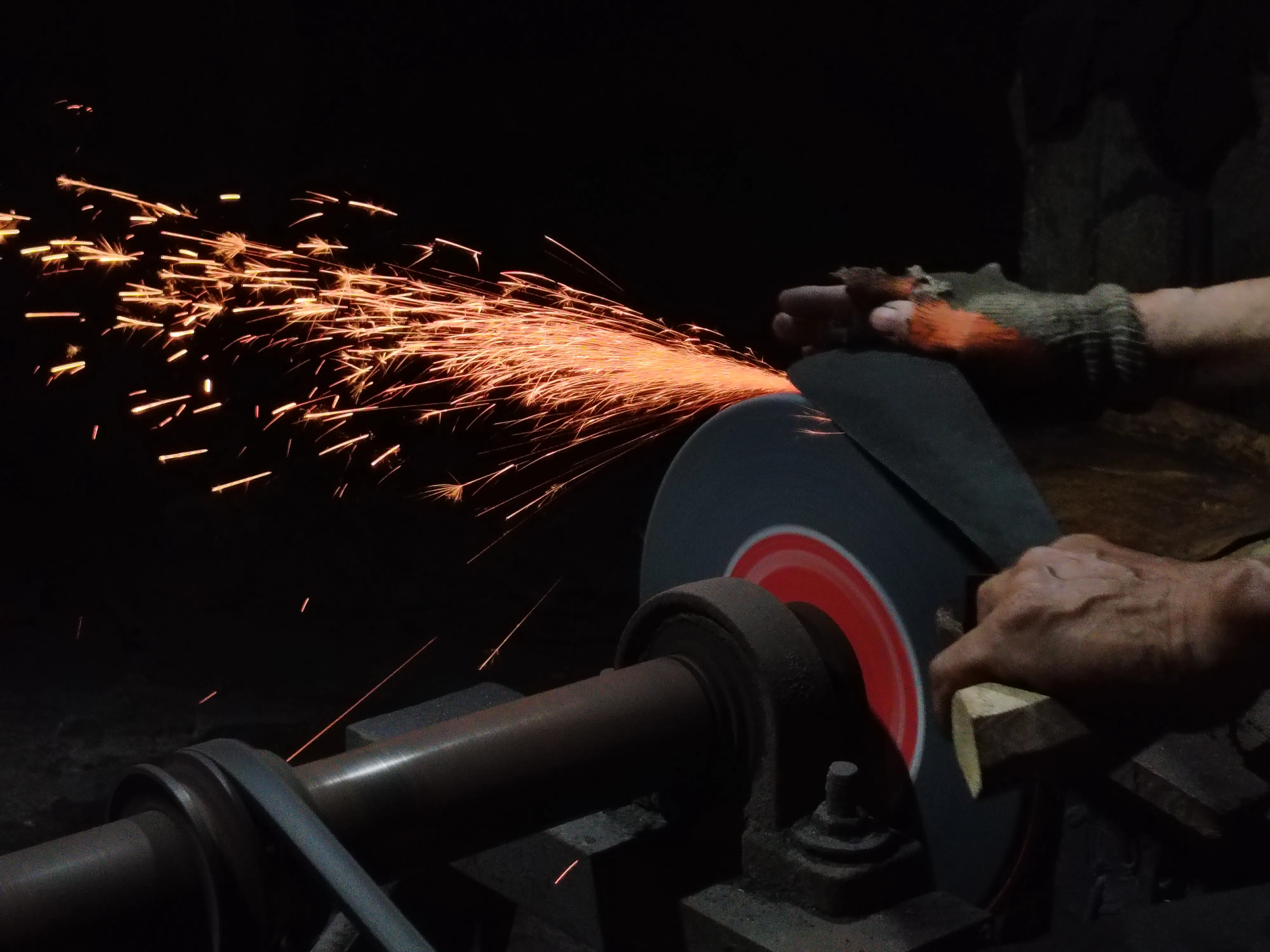 An image of a person using grinder to sharpen a tool.